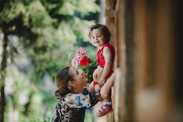 Pretty little girl looks down sitting outside on wooden windowsill