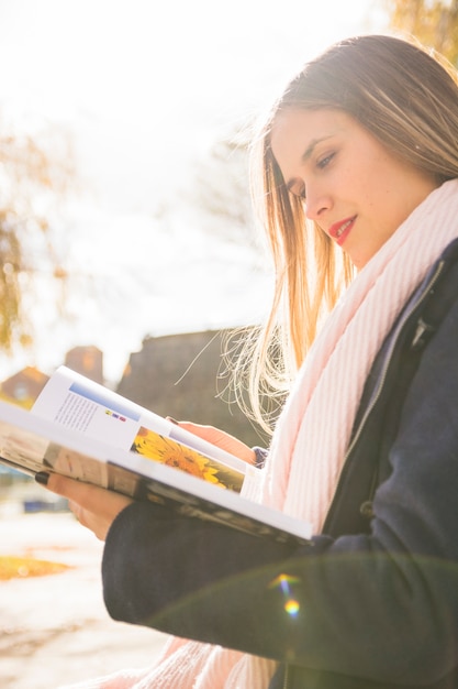 Free photo pretty model female reading book in shiny autumn