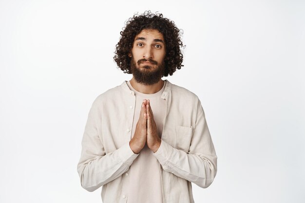 Pretty please Coy handsome middle eastern guy asking for smth begging you standing over white background