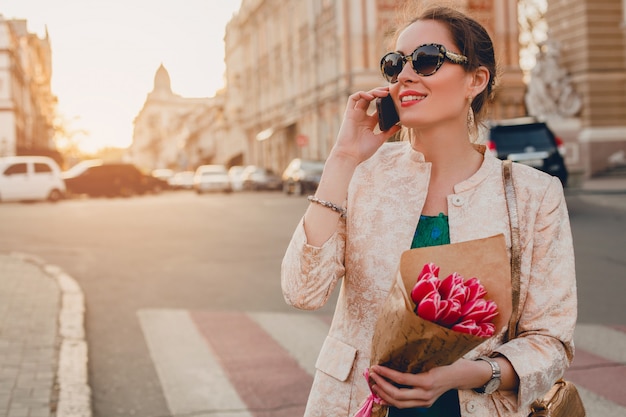 Pretty portrait of young stylish attractive woman walking in city and talking at the phone