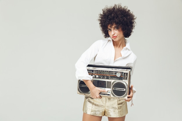 Free photo pretty retro woman holding boombox.