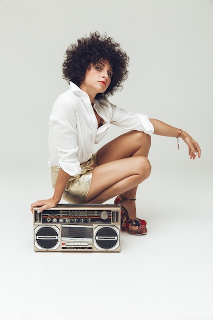 Pretty retro woman near boombox.