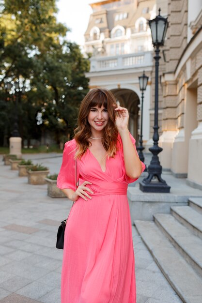 Pretty romantic woman in pink dress posing outdoor in old european ity.