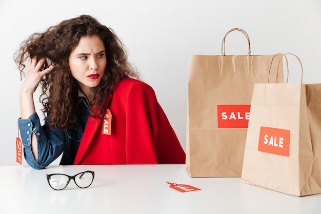 Pretty sale woman sitting and looking at paper shopping bags