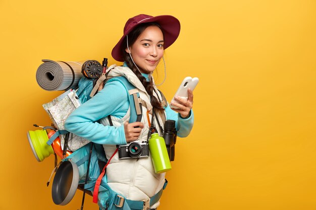 かなり満足している旅行者は、放浪癖の旅行中にブログにスマートフォンで無料のインターネット接続を使用し、大きな重いリュックサックを運びます