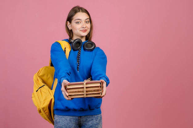 Graziosa scolara in piedi che tiene mazzo di vecchi libri