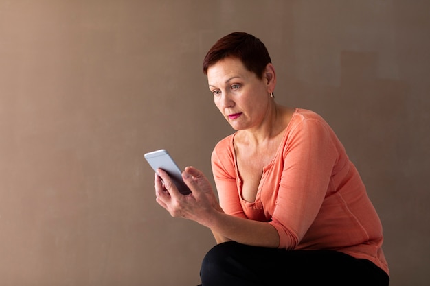 Pretty senior woman checking smartphone