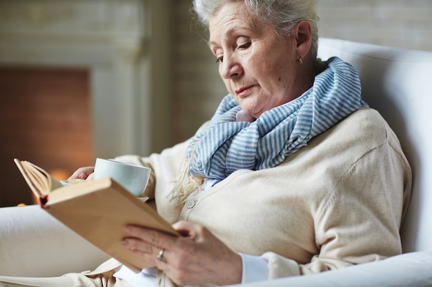 Pretty senior woman reading book