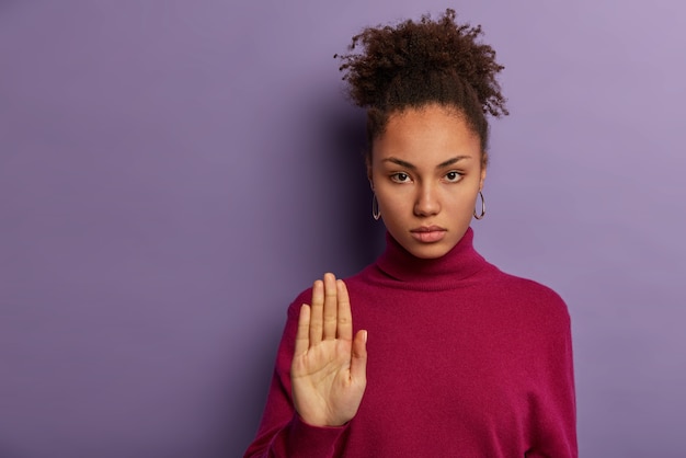 Foto gratuita una donna abbastanza seria tira il palmo, non mostra alcun gesto di rifiuto, rifiuta o dice aspetta, vestita con un collo casual casual, non essendo interessata a qualcosa, cerca di calmare qualcuno. fermati qui