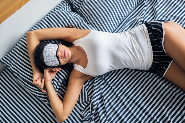 Pretty sexy woman lying in bed in morning, wake up early, sleeping in mask