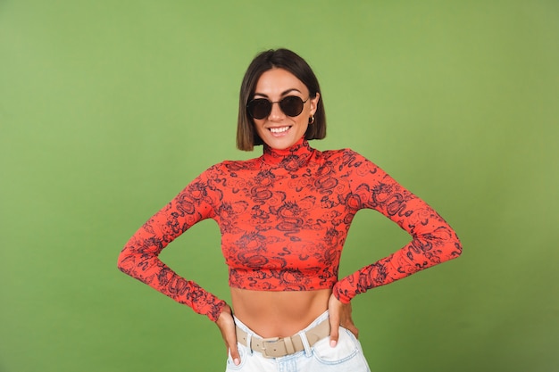 Pretty short hair woman with golden earrings, sunglasses, red china dragon printed blouse on green