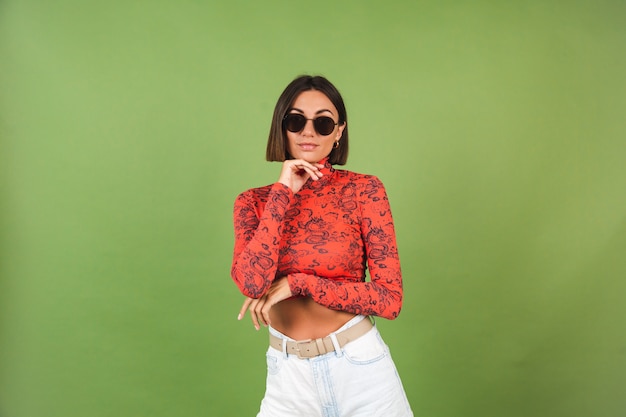 Pretty short hair woman with golden earrings, sunglasses, red china dragon printed blouse on green