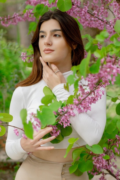 Free photo pretty slim girl wearing stylish clothes looking forward holding lilac by hands