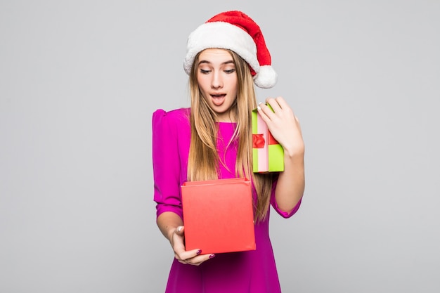 La ragazza felice divertente abbastanza sorridente in breve vestito rosa e cappello del nuovo anno tiene la sorpresa della scatola di carta nelle sue mani