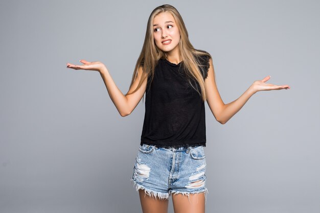 Pretty smiling woman in black shirt isolated on gray background asking you to make a choice between two products