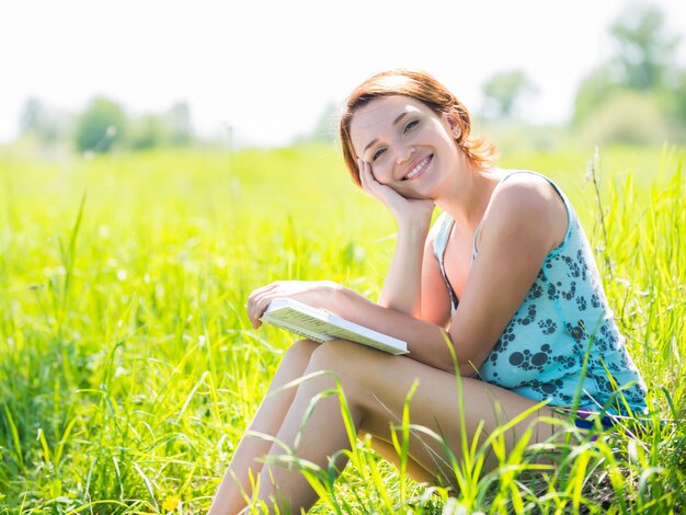 かなり笑顔の女性が自然の中で本を読む