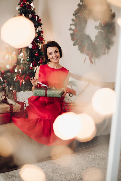 クリスマスプレゼントと彼女の寝室に座っているかなり笑顔の女性