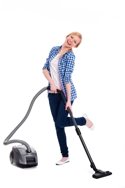 예쁘고 웃는 여자는 바닥을 진공 청소기로 청소