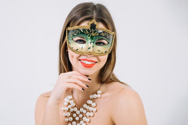 Милая усмехаясь женщина нося зеленую декоративную карнавальную маску