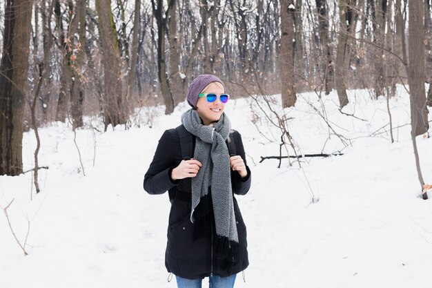 冬の間に雪に覆われた風景の中にバックパック立って保持暖かい服装でかなり笑顔の女性