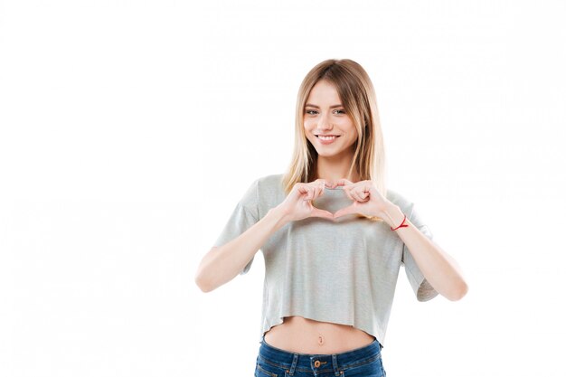 Pretty smiling young woman showing heart gesture with two hands