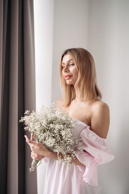 Free photo pretty smiling young woman standing with a bouquet of flowers