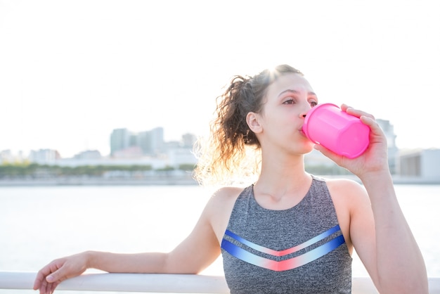 Pretty Sporty Girl Drinking From Shaker Outdoors