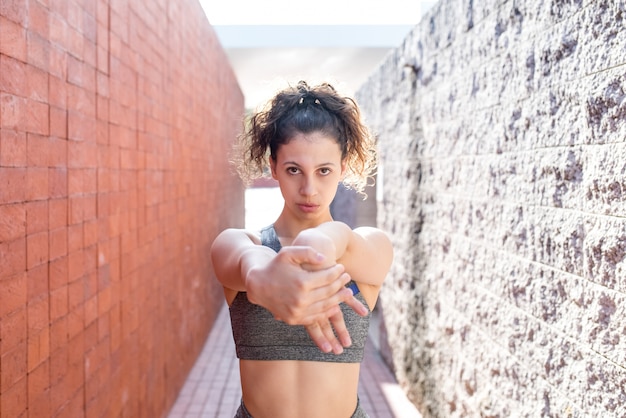 Ragazza graziosa sportiva che si stende le braccia tra le pareti