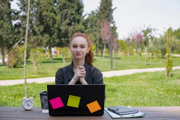 Pretty student sitting working at laptop holding hands in lock