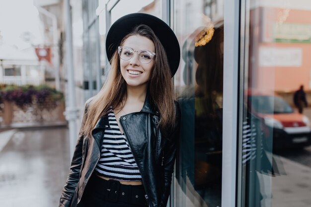 Pretty stylish girl walks on the street in black leather jacket after rain