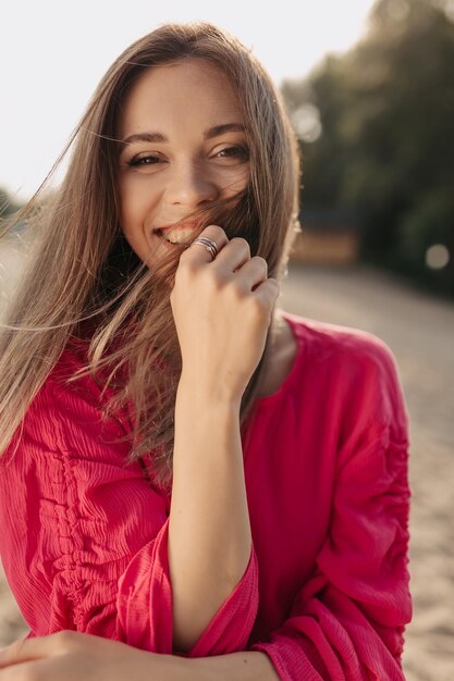 サングラスと灰色のポンチョを着たかなりスタイリッシュな女性が日当たりの良い通りを屋外でコーヒーを飲みながら歩いています