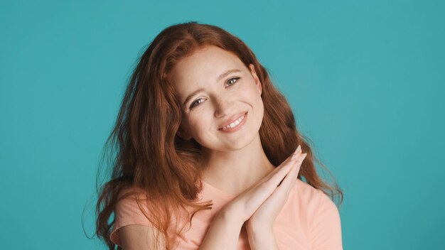 Pretty surprised redhead woman happily looking in camera and smiling over blue background Excited expression