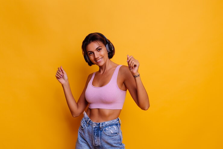Free Photo pretty tanned woman with perfect abs wearing headphones, dancing and listening to music