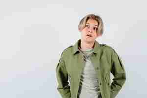 Free photo pretty teen boy in green jacket looking upward and looking thoughtful , front view.