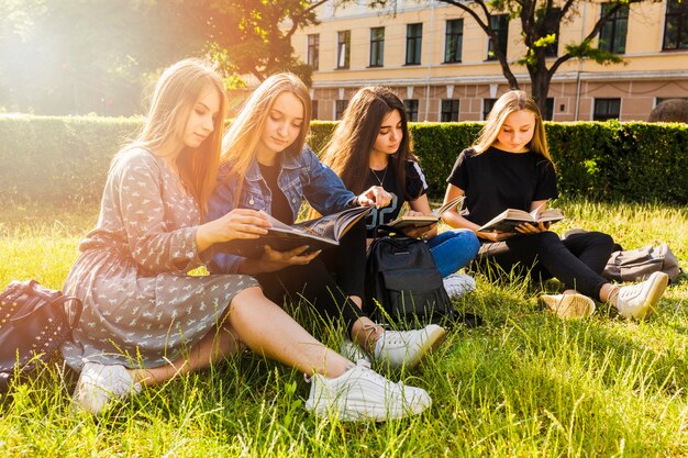 Pretty teen girls reading in park