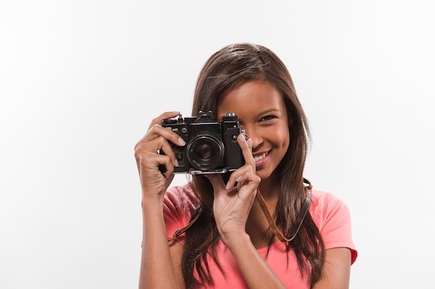 Pretty teenage girl clicking photograph through vintage camera