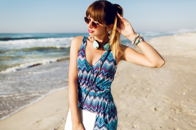 Pretty traveler woman using tablet on sunny beach