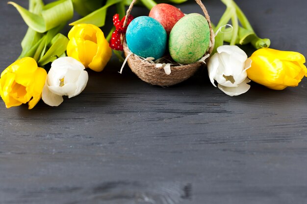 Pretty tulips near basket with eggs