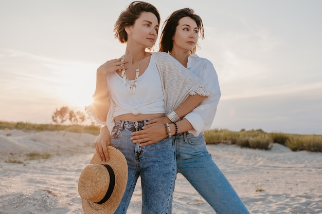 Pretty two young women having fun on the sunset beach, gay lesbian love romance