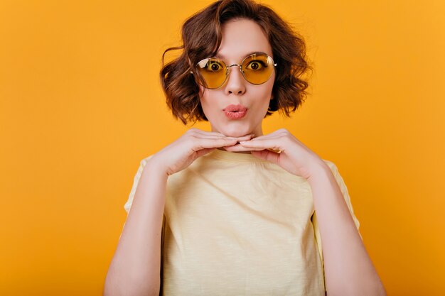 Pretty white woman with dark wavy hair posing on yellow space