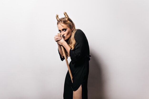 Pretty witch in black outfit standing . Good-looking girl in carnival attire posing after halloween party.