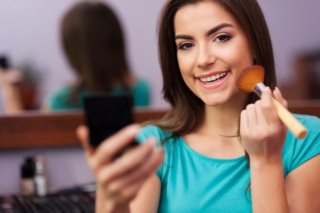 Pretty woman applying face powder