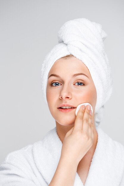 Pretty woman in bathrobe take-off makeup with cleanser