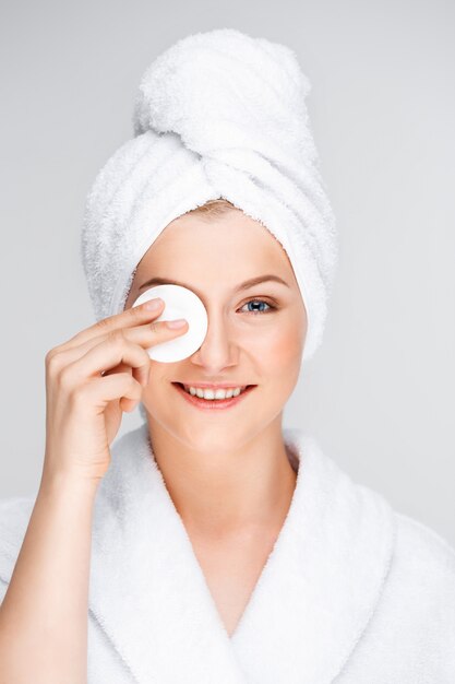 Pretty woman in bathrobe take-off makeup with cleanser