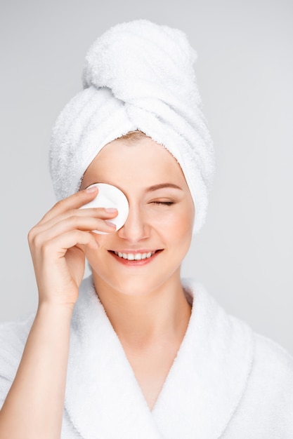 Free photo pretty woman in bathrobe take-off makeup with cleanser