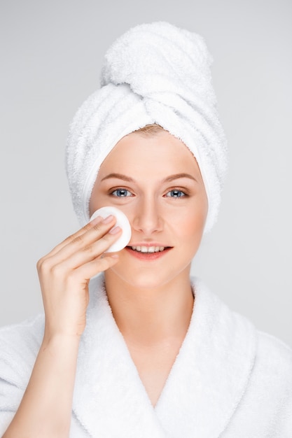 Pretty woman in bathrobe take-off makeup with sponge