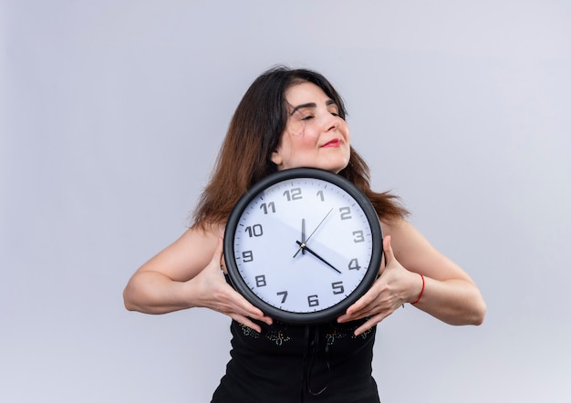 Pretty woman in black blouse happily hugging clock 