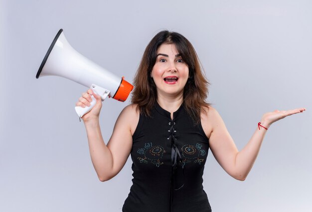 Pretty woman in black blouse holding megaphone happily 