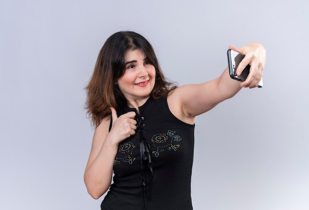 Pretty woman in black blouse looks happy making selfie 