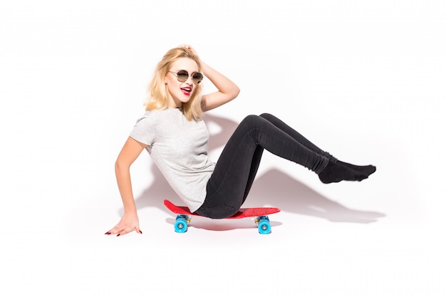 Pretty woman in black jeans sit on red skateboard